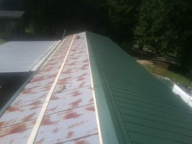 Old rusted panels beside newly installed green metal roofing — Wind Damage Roof Repair by Roofing Brothers in Plympton