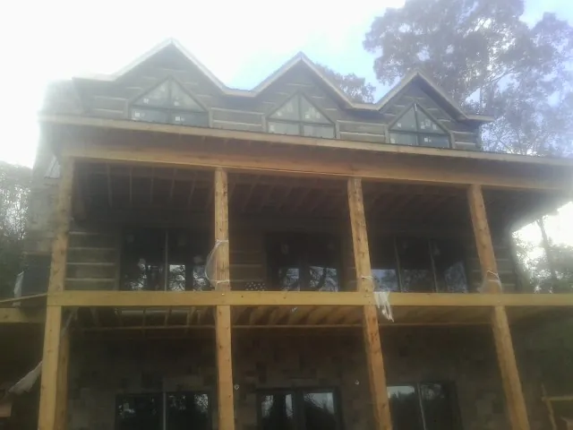 Dormers and porch framing on a large log home under construction — Roof Coating work by our crew in Plympton