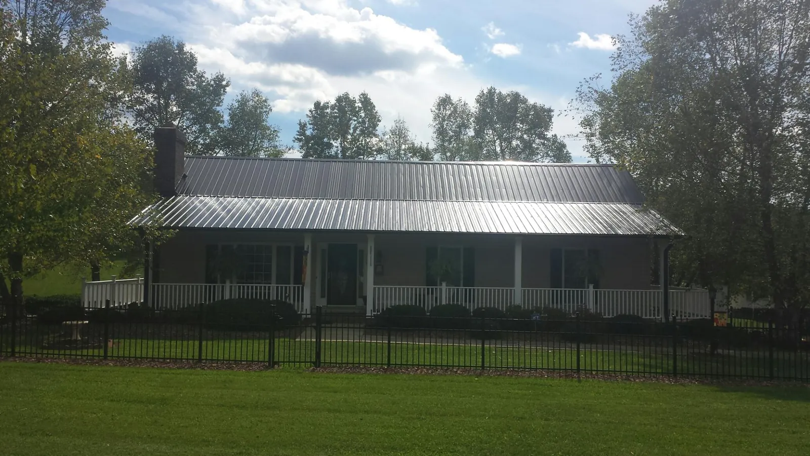 Gray metal roof on a brick ranch with a full width front porch — Gutter Guard Installation work by our crew in Plympton