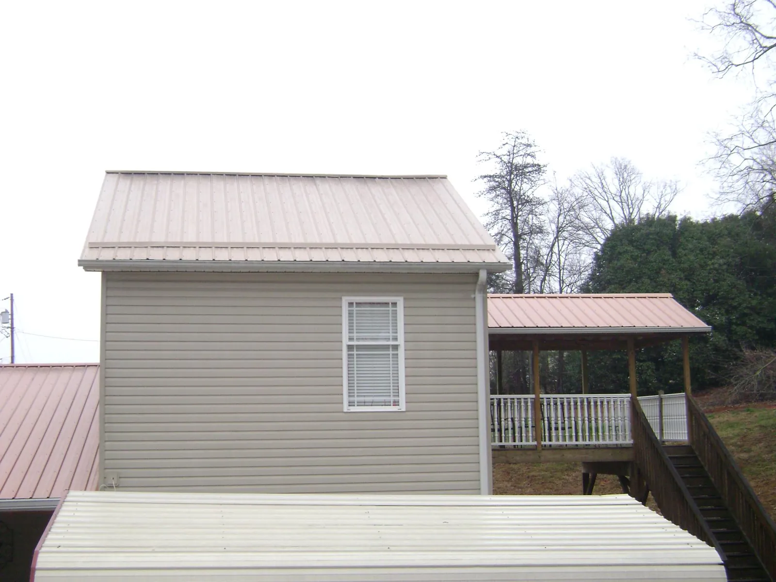Tan metal roofs on a two story addition and attached porch, from a Roof Replacement job in Plympton