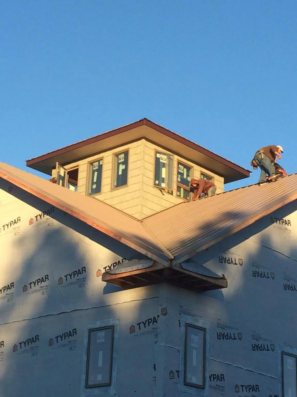 Roofers working around a rooftop cupola on a new metal roof at sunset — Roof Waterproofing in Plympton by Roofing Brothers